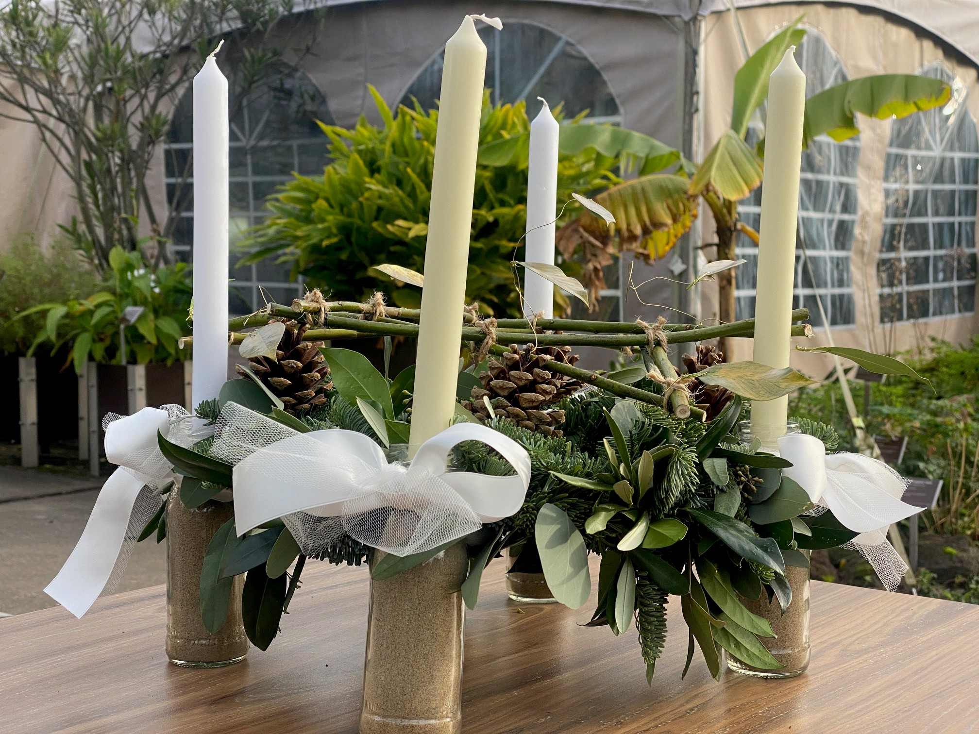 Handgemaakte adventskrans met wintergroen en vier witte kaarsen staan prachtig op een gedekte tafel.